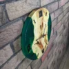 Side view of maple wood and emerald green epoxy wall clock mounted on an exposed brick wall