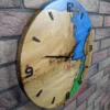 Side view of round oak wood wall clock featuring blue and green epoxy resin inlay, mounted on a brick wall.