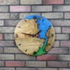 Round wall clock of light wood and blue-green epoxy resin, with black hands and markers, on a multi-colored brick wall.
