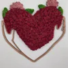 Heart-shaped preserved moss wall art framed by a wooden outline of embracing arms on a white wall.