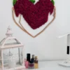 Heart-shaped magenta moss wall art in wood frame hanging above white dresser with lantern and perfume bottles