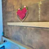 Heart-shaped magenta moss wall art displayed above a headboard shelf on a textured brown bedroom accent wall