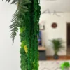 Close-up of mirror frame detailing textured green reindeer moss, draped foliage, and fern leaves.