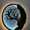Backlit round Tree of Life dryad wall art with glowing LED light highlighting black silhouette and green moss.