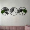 Three-piece round wall decor set with ginkgo leaf silhouettes and preserved moss accents mounted above a daybed