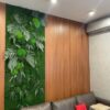 Vertical green moss wall with preserved ferns and bun moss on a wood-paneled wall behind a leather sofa.
