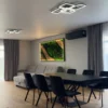 Backlit moss and wood wall art hanging in an open-plan room, viewed behind a black dining table and chairs