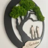 Angled view of round black wood family tree wall art with green preserved moss and an engraved wooden plaque.