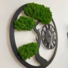 Angled view of round black wood wall clock with bonsai tree silhouette and green reindeer moss on a white wall