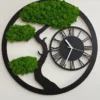Round black wooden wall clock featuring a tree silhouette with green reindeer moss and Roman numeral dial