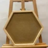 Front view of an empty natural wood hexagon shadow box frame resting on a wooden easel