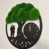 Angled view of black tree of life wall clock with green moss foliage and couple silhouette mounted on wall