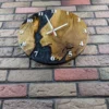 Round oak and black epoxy resin wall clock with white numerals, shown close-up on a brick wall