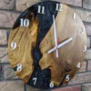 Round wooden wall clock with epoxy resin river design and numerals on a brick wall
