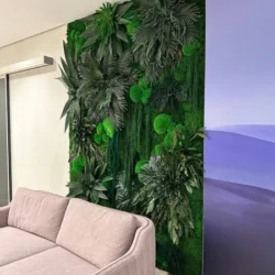 Preserved plant and moss wall art installation mounted in an interior living space behind a sofa.