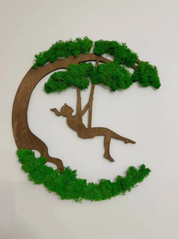 Round moss wall art featuring a wooden silhouette of a girl on a swing under a tree canopy