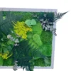 Preserved green moss wall art with ferns and eucalyptus extending over a white frame
