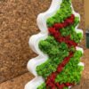 Side view of white wooden Christmas tree filled with green reindeer moss and a red moss garland