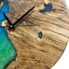 Close-up of round oak wood wall clock with blue and green epoxy resin fill and black hands