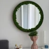 Round wall mirror bordered with preserved reindeer moss hanging above a white vanity table