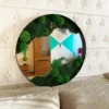 Black-framed round mirror with green moss and plants, mounted on a white tufted wall above a beige sofa.