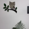 Wall decoration of an owl on a branch made of brown and green moss above a houseplant.