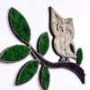 Wooden silhouette of an owl on a branch, filled with green and light moss
