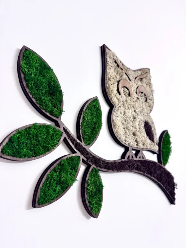 Wooden silhouette of an owl on a branch, filled with green and light moss