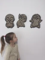 A small girl looks at three fluffy penguin-shaped wall decorations on a white wall.